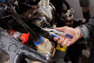 A clickable image of a mechanic using a hand tool to adjust an engine part