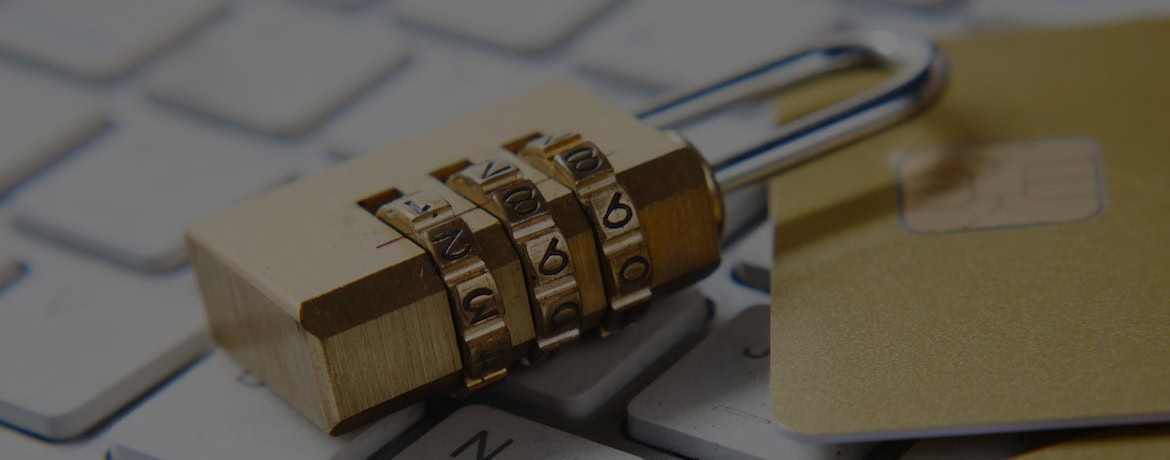 Close-up of a gold combination padlock securing a computer keyboard and a credit card, symbolising online security and privacy.
