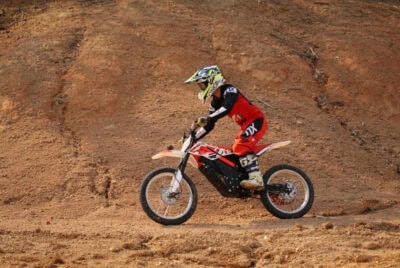 Motocross rider in full gear riding on a dirt track, showcasing Grand Prix Racewear for off-road motorcycle racing.