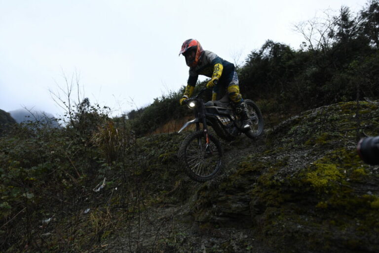 Motocross rider wearing Grand Prix Racewear navigating rocky terrain on a mountain trail.