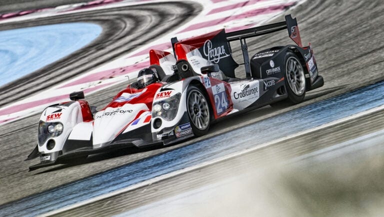 High-speed race car on a racing circuit with colourful track markings, showcasing Grand Prix Racewear branding and racing livery.