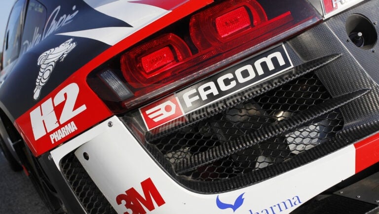 Close-up of a race car rear with sponsor logos, including Facom, 3M, and Pharma, showcasing Grand Prix Racewear racing gear.