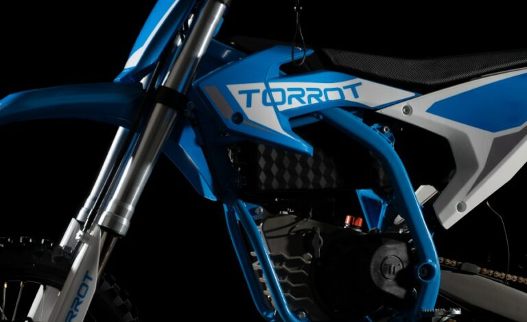 Close-up of a blue and white Torrot electric motorcycle showcasing its frame and suspension system for Grand Prix Racewear.