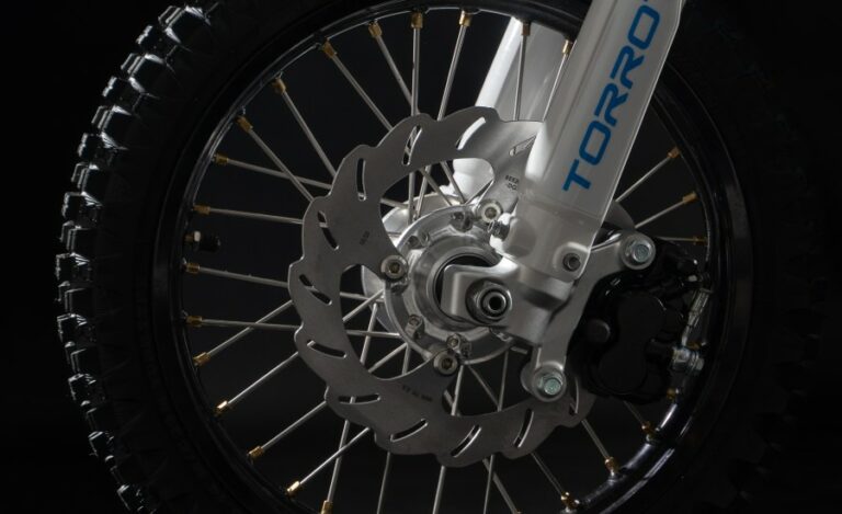 Close-up of a motorcycle front wheel with disc brake and suspension, showcasing high-performance racing components.