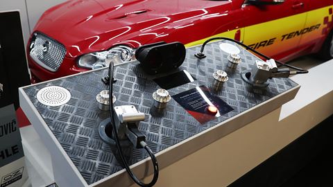 Grand Prix Racewear display featuring racing communication devices and accessories at an automotive event.