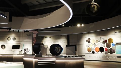 Exhibition display at Grand Prix Racewear showcasing racing tyres, helmets, and racing gear in a modern showroom setting.
