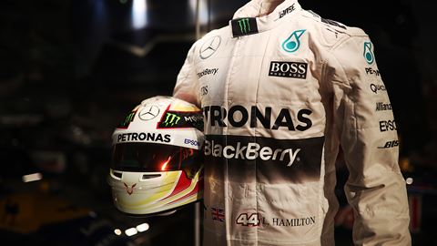 Formula 1 driver Lewis Hamilton in his Mercedes racing suit holding a helmet, showcasing Grand Prix Racewear gear for motorsport enthusiasts.