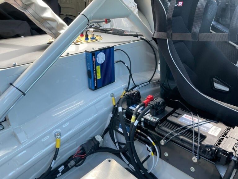 Close-up of racing car interior showing electronic components, wiring, and safety harnesses for high-performance motorsport.