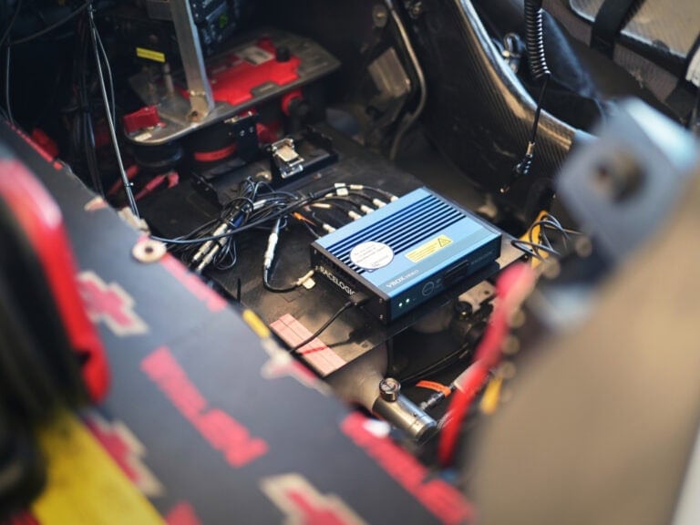 Close-up of racing car electronics and wiring, showcasing high-performance components used in Grand Prix racewear.