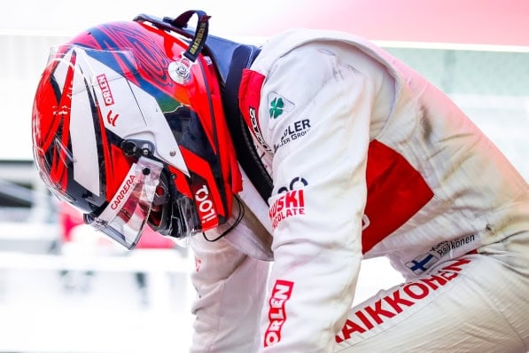 Close-up of a racing driver in a Sparco racing suit and helmet, preparing for a race at a professional circuit.