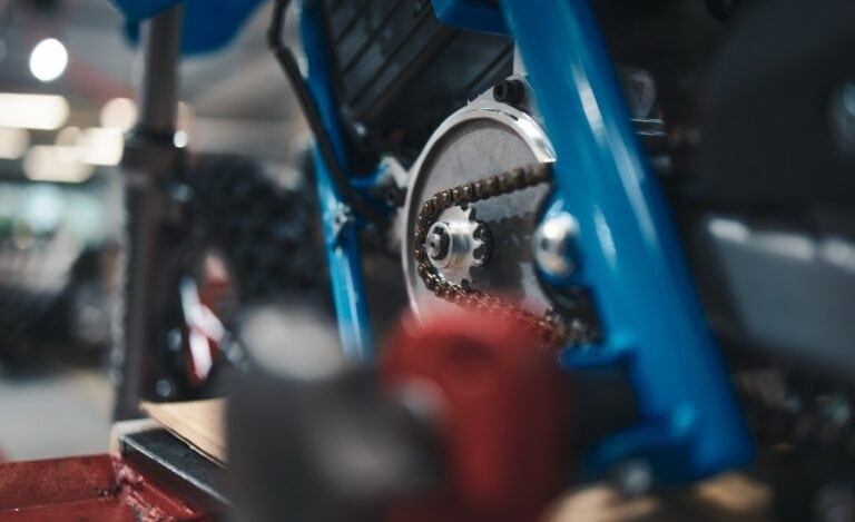 Close-up of a high-performance motorcycle suspension system with purple and blue components at a racing event.