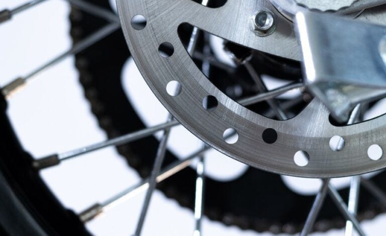 Close-up of a motorcycle disc brake and wheel spokes, highlighting high-performance racing components.