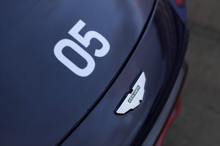 Close-up of a dark blue Aston Martin car with the number 05 and the Aston Martin logo on the hood.