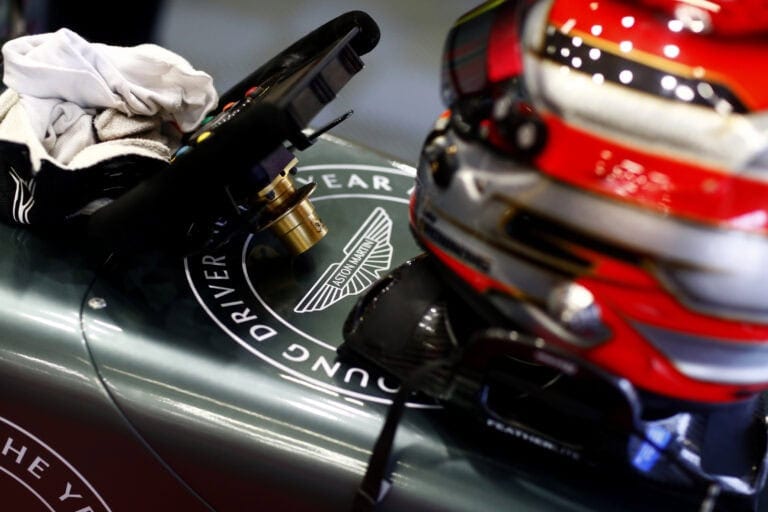Close-up of a racing helmet and racing car with Grand Prix Racewear branding, highlighting motorsport safety gear and racing equipment.