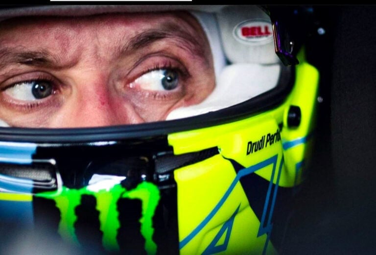 Close-up of a race car driver wearing a Bell helmet with a focus on the eye and helmet design.