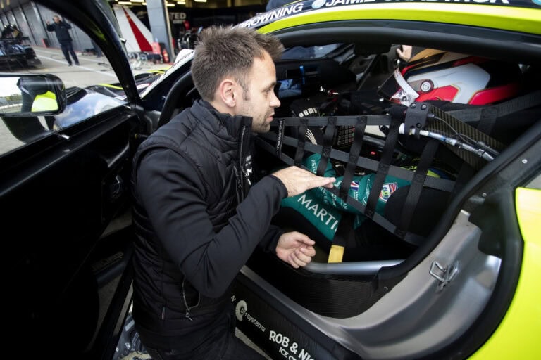 Race car driver preparing safety gear in the cockpit for a track day at Grand Prix Racewear.