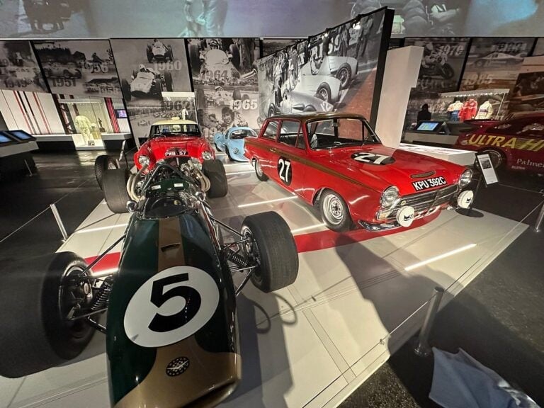 Classic race cars on display at Silverstone Heritage Museum, including a vintage Formula 1 car and a red sports car with racing numbers.