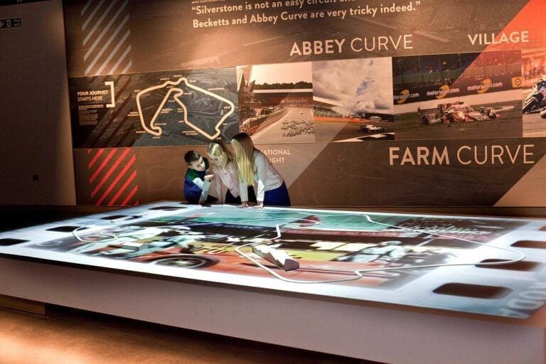 Interactive racing track display at Silverstone Heritage Museum with visitors exploring the exhibit.