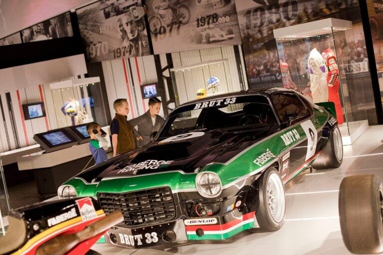 Classic green and black race car on display at Silverstone Heritage Museum with visitors observing.