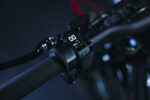 Close-up of a digital bike speedometer mounted on a textured handlebar with a dark background.