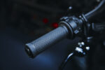 Close-up of a motorcycle handlebar grip with textured rubber surface and control components.