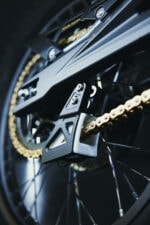 Close-up of a high-performance bicycle chain and gear system with black and gold components.
