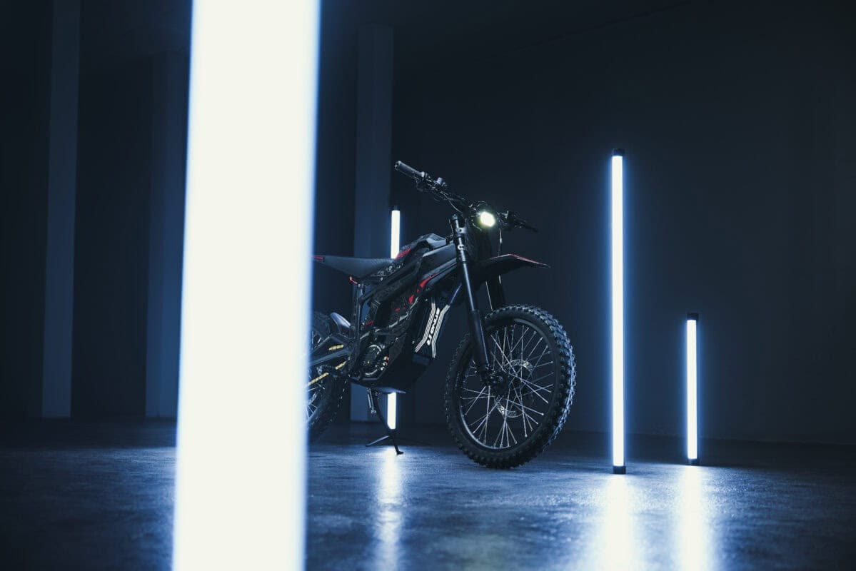 Electric mountain bike showcased in a dark room with vertical LED light strips highlighting its features.