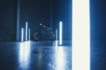 Electric dirt bike showcased in a dark room with vertical blue LED light bars highlighting its features.