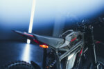 Close-up of a high-performance electric motocross bike with sleek black and red design, showcasing advanced racing features and durable tires for off-road racing.