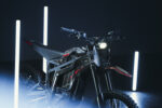 Electric mountain bike with sleek black and red design, illuminated by vertical LED lights in a dark setting.