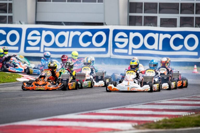 High-speed go-kart race with multiple racers on track, featuring Grand Prix Racewear branding in the background.