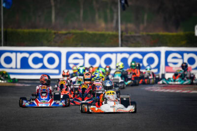 Close-up of go-karts racing on a track with Grand Prix Racewear branding in the background.