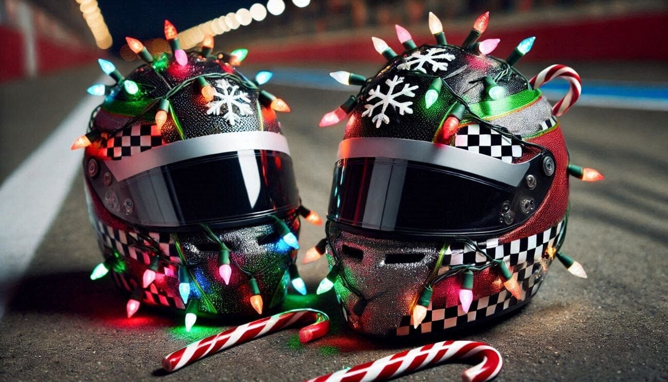 Two racing helmets decorated with Christmas lights, snowflakes, and candy canes on a race track.