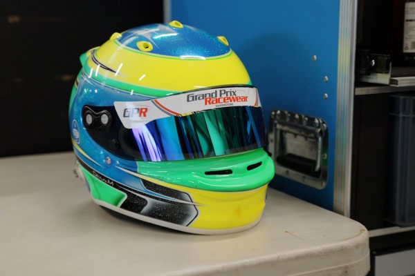 Colorful Grand Prix Racewear helmet with reflective visor on a table, ideal for motorsport safety and racing events.