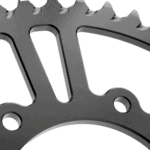 Close-up of a metallic gear or sprocket used in racing or mechanical applications, showcasing precision engineering and durability.