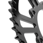 Close-up of a black metal sprocket gear used in racing vehicles, highlighting its teeth and precision engineering.