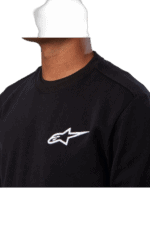 Close-up of a person wearing a black Grand Prix Racewear sweatshirt with Alpinestars logo, suitable for motorsport enthusiasts.