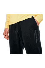 Close-up of a person wearing black Grand Prix Racewear sweatpants with logo, yellow long-sleeve top, and hand in pocket, showcasing racing apparel.