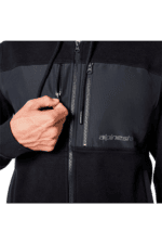 Close-up of a person adjusting a black and grey Alpinestars racing jacket with a front zipper and chest pocket.
