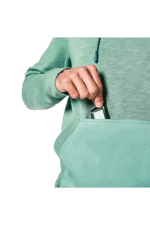 Close-up of a person in a green hoodie placing a smartphone into a light green bag, with a focus on the hand and bag.