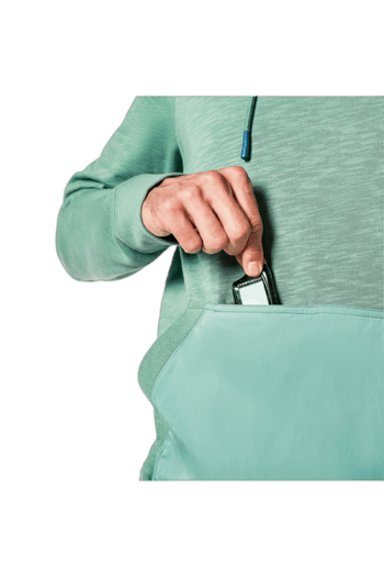 Close-up of a person in a green hoodie placing a smartphone into a light green bag, with a focus on the hand and bag.