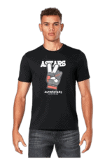 Young male model wearing a black Grand Prix Racewear T-shirt with a peace sign graphic and 'ALPINESTARS' logo, showcasing motorsport apparel.