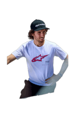 Young male motocross rider wearing Alpinestars cap and T-shirt, smiling confidently, representing Grand Prix Racewear for motorsport apparel.