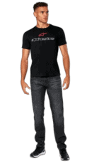 Man wearing Alpinestars racing t-shirt and jeans, standing confidently against a plain background.