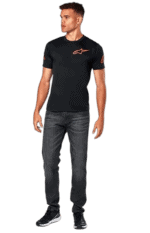 Man wearing black Alpinestars racing T-shirt and jeans, standing outdoors.