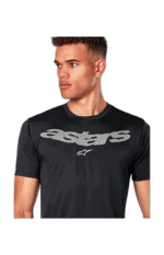 Young man wearing a black Alpinestars racing T-shirt with logo, looking to the side.