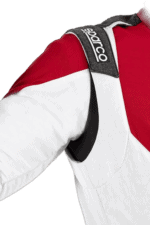 Close-up of a racing driver wearing a red and white racing suit with Sparco branding on the shoulder strap.