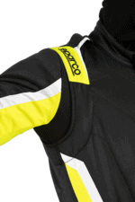 Close-up of a racing driver wearing a black and yellow Grand Prix Racewear suit with Sparco branding on the shoulder.