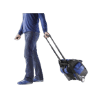 Person pulling a blue and black racing gear bag on wheels, wearing jeans and a blue sweater.