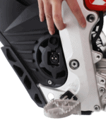 Close-up of a mechanic's hand working on a motorcycle engine, focusing on the electrical connector and engine components.